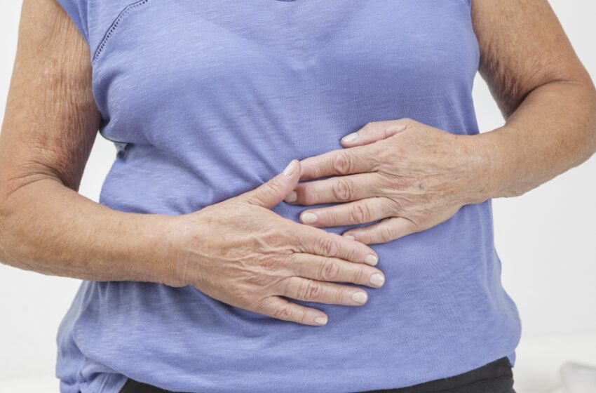 mature woman with leaky gut holding her stomach